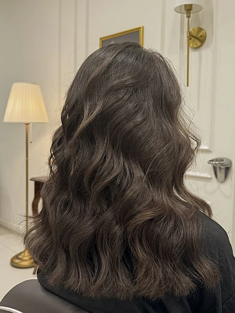 una ragazza seduta di spalle con lunghi capelli castani seduta su una poltroncina del salone