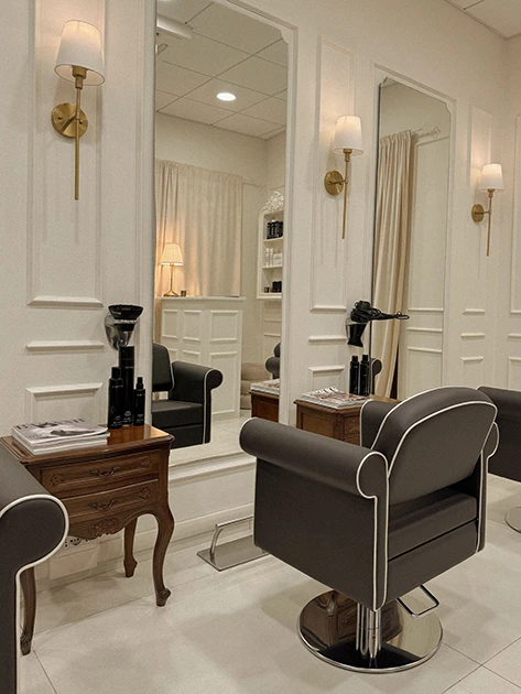 la postazione di un salone di parrucchieri con una poltroncina, uno specchio e un asciugapelli